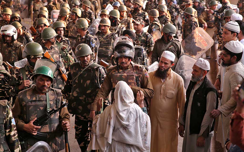 A woman speaks with a police officer during a sit-in protest in a riot affected area after clashes erupted between people demonstrating for and against a new citizenship law in New Delhi
