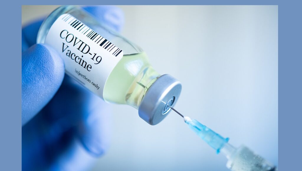 Doctor drawing up Covid-19 vaccine from phial bottle and filling
